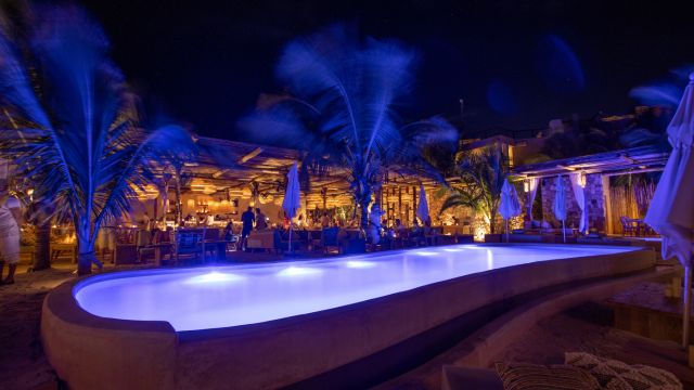 Piscina iluminada y ambiente nocturno en Tantra Beach Club Tulum